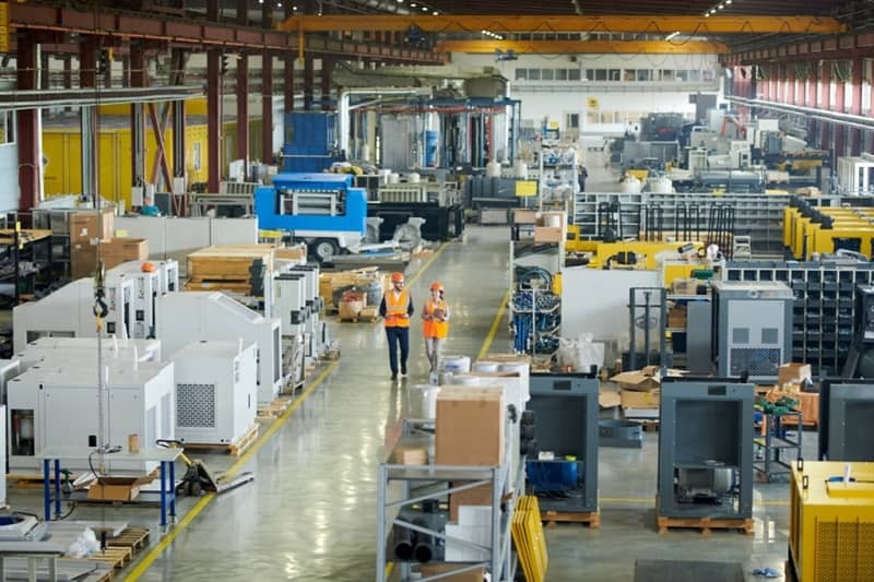 Zwei Techniker auf dem Weg durch eine Fabrikhalle.
