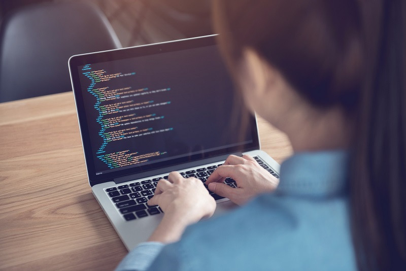 A woman using her laptop, working on coding.