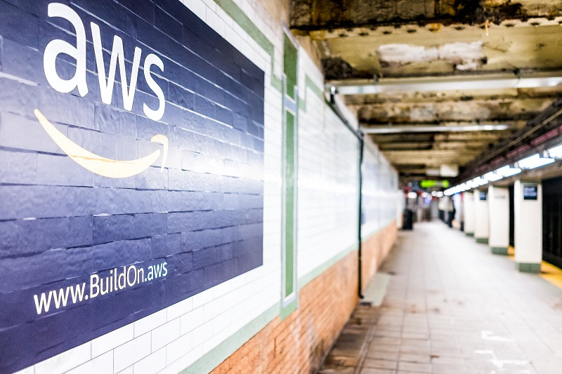 A picture of the Amazon AWS logo painted on a brick wall.