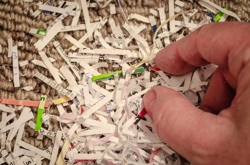 A hand picking from a stack of shredded paper.