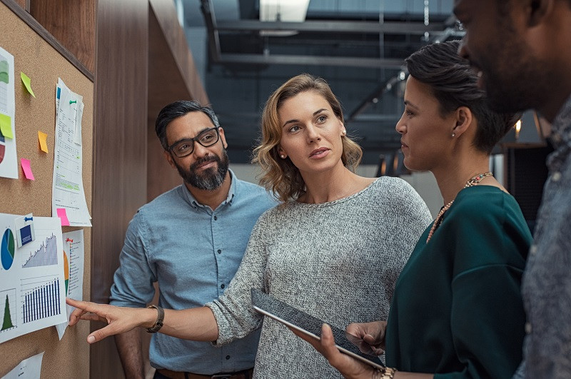 A group of coworkers discussing a poster board.