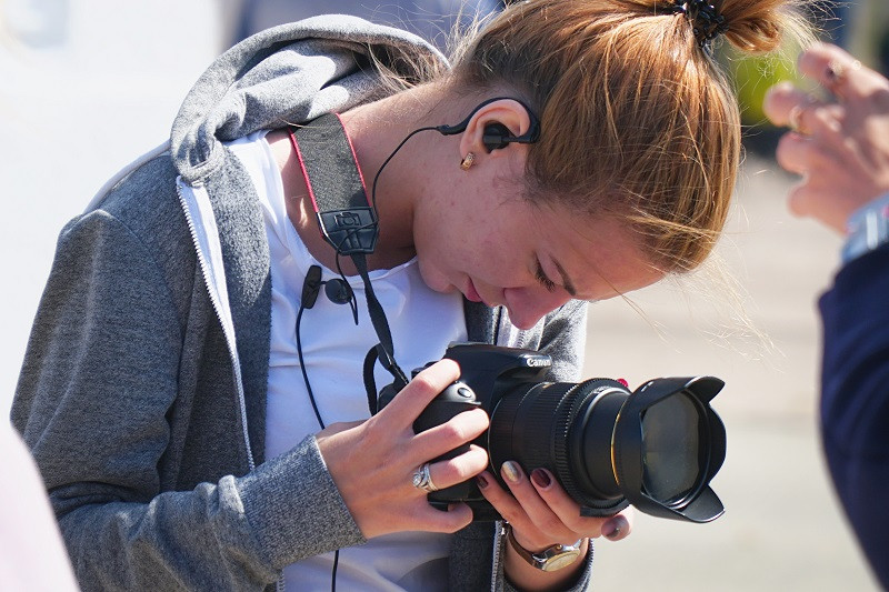 A young woman using a Canon camera.