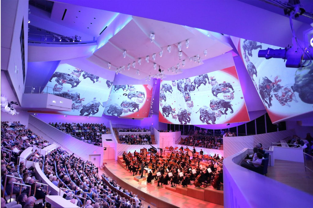 A picture of a concert hall with orchestra and audience.