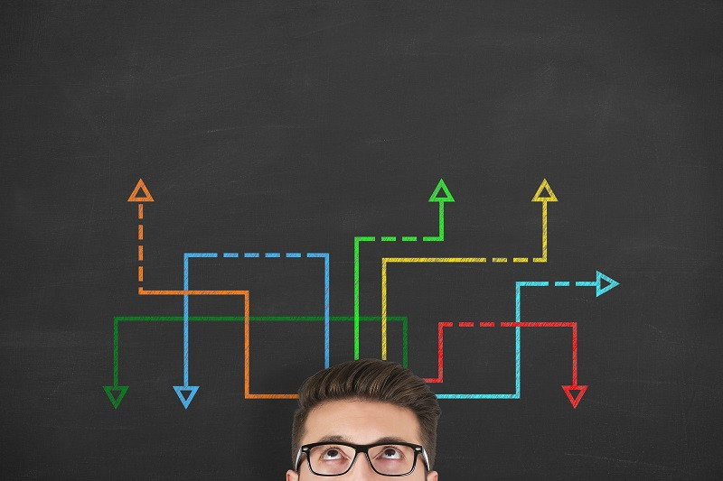 A man looking above at multi-colored arrows.