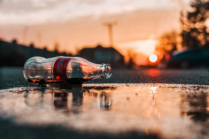 A Coke bottle in a puddle.