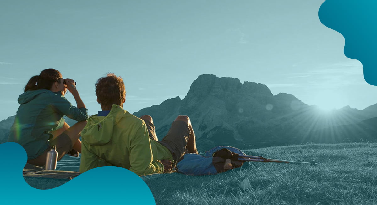 IDM Südtirol header image in blue of couple enjoying scenic environment.