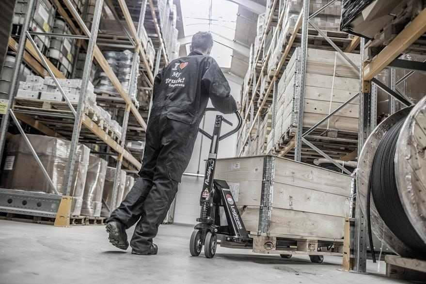 Screenshot of a Logitrans asset in Canto, showing a person in a coverall pushing a loaded cart through the warehouse.