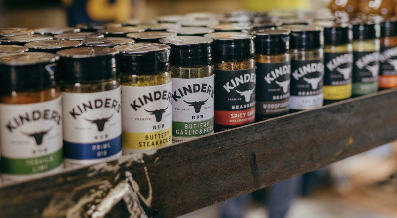 An image of a grocery shelf with Kinder's seasonings lining the entire shelf row.