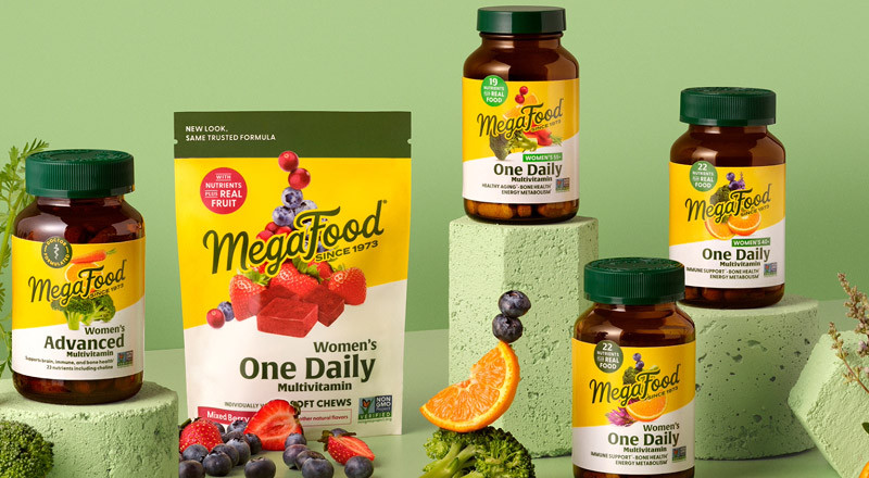 MegaFood supplements and vitamin packages with different berries, oranges and broccoli on light green concrete shapes over a light green background