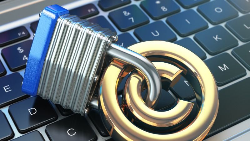 A padlock securing a copyright symbol on top of a laptop keyboard.