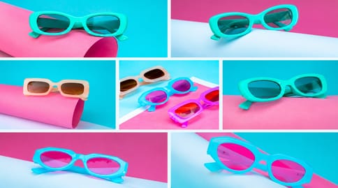 Colorful sunglasses laid out on pink and blue paper