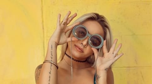 Frau mit runder Brille vor einer gelben Wand